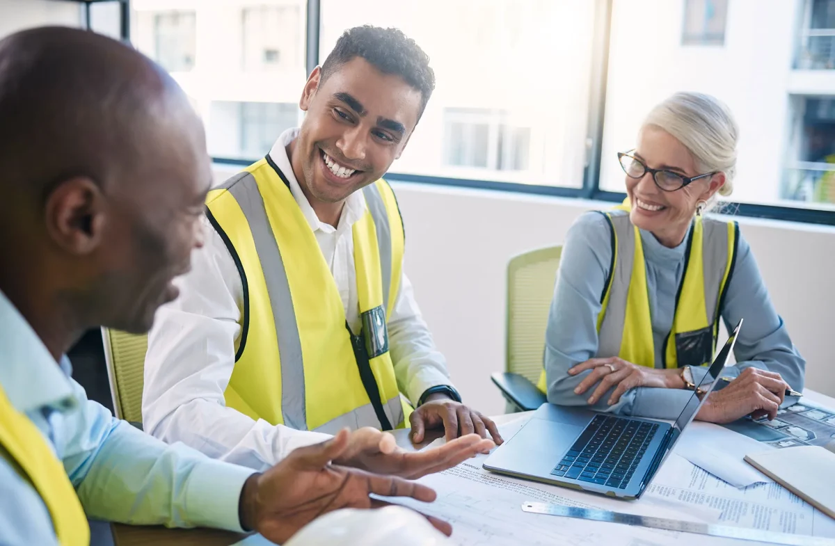 hree individuals in safety vests engaged in conversation outdoors