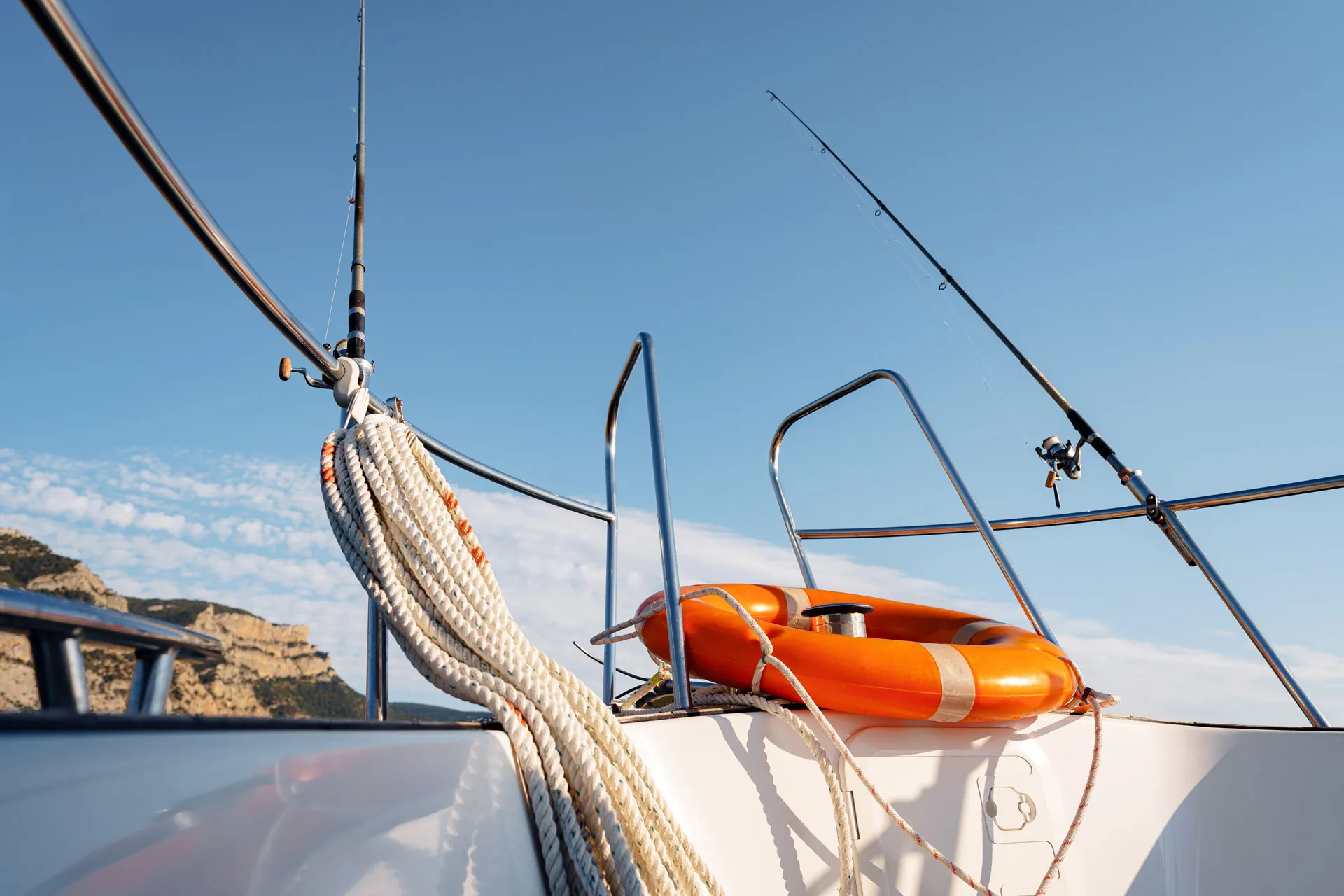 A white boat with a red life preserver attached, floating on calm water under a clear blue sky