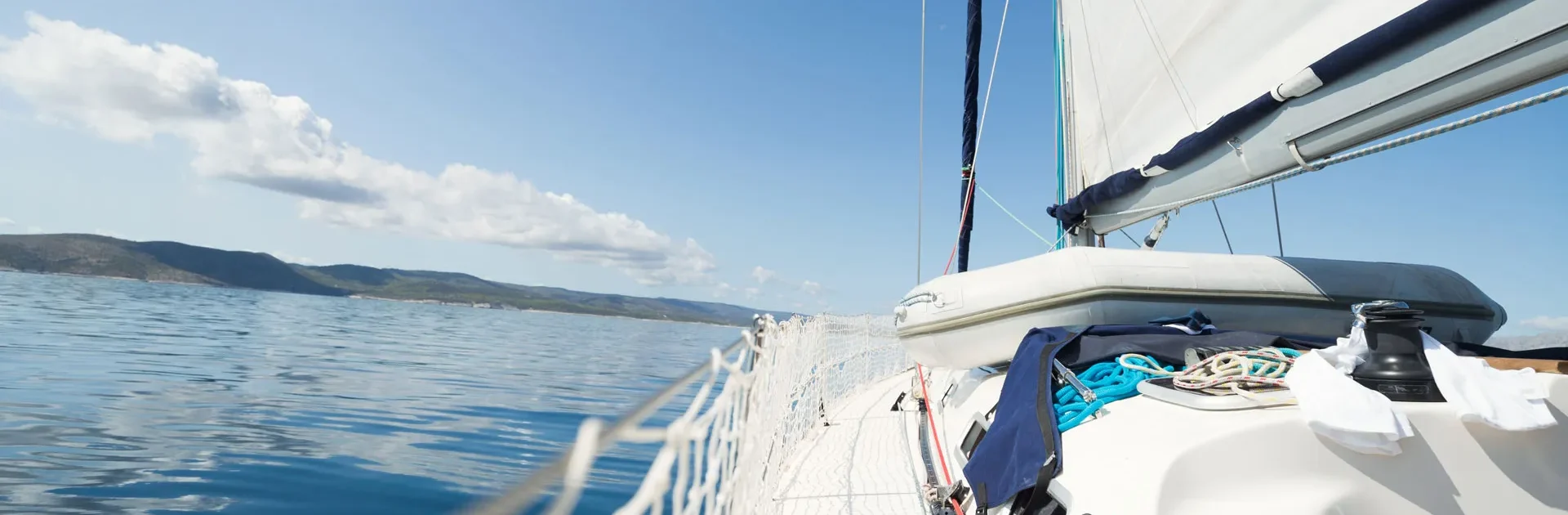 A sailboat gliding across calm water under a clear blue sky