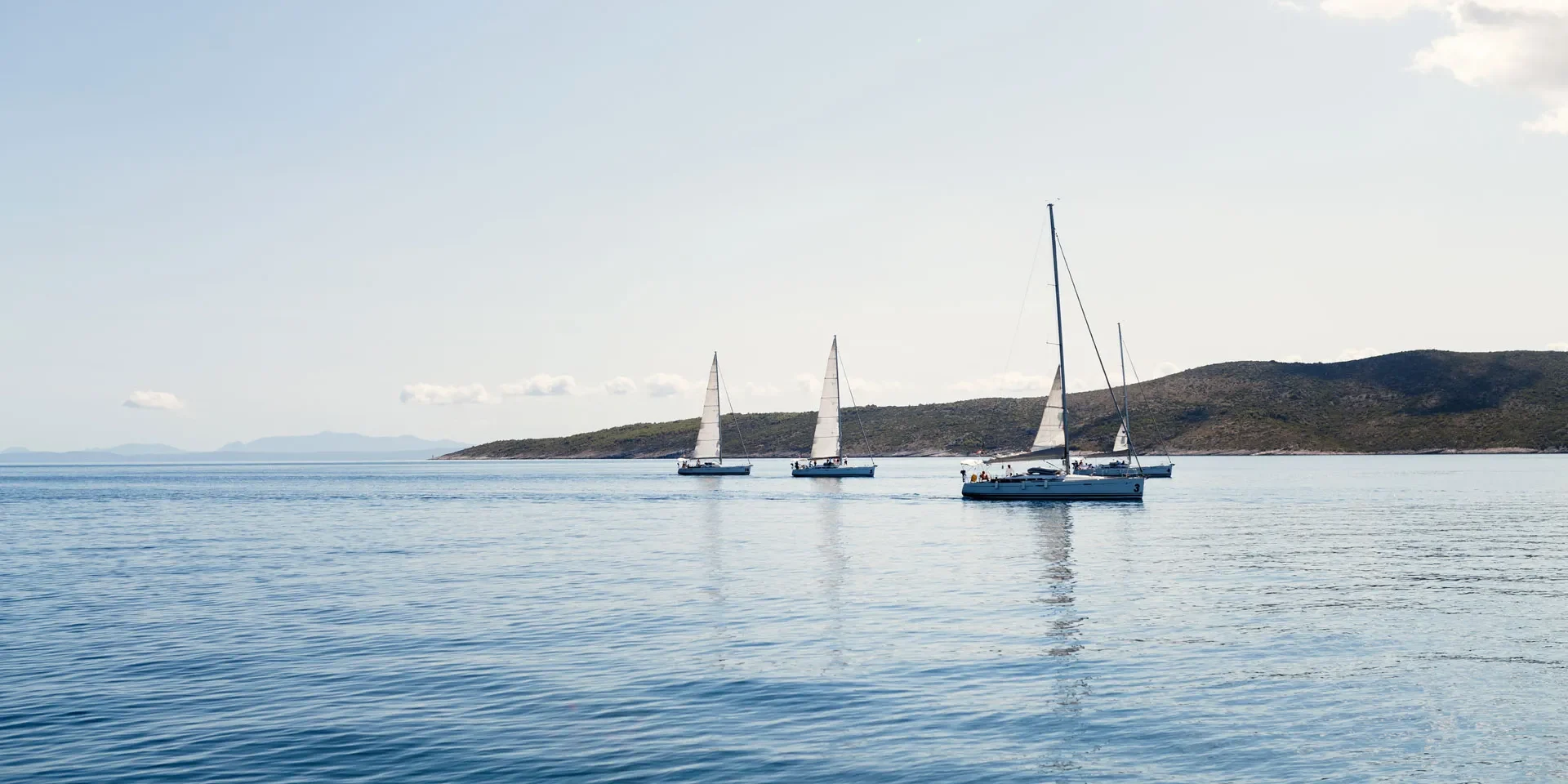 A group of colorful sailboats floating on calm water under a clear blue sky